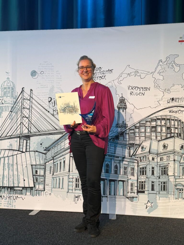 Frau steht vor dem IHK Banner und hält eine Urkunde